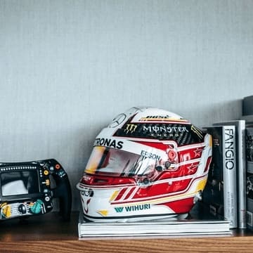 High quality Lewis Hamilton Replica Scale helmet with a replica steering wheel and vintage f1 books on a wooden shelve.