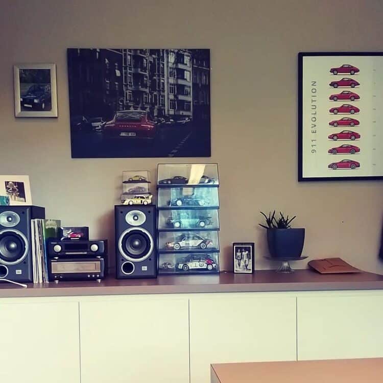 Office or livingroom decration. A porsche fan with two porsche posters in the wall. On top of the shelves you can see a collection of model cars and diecast cars.